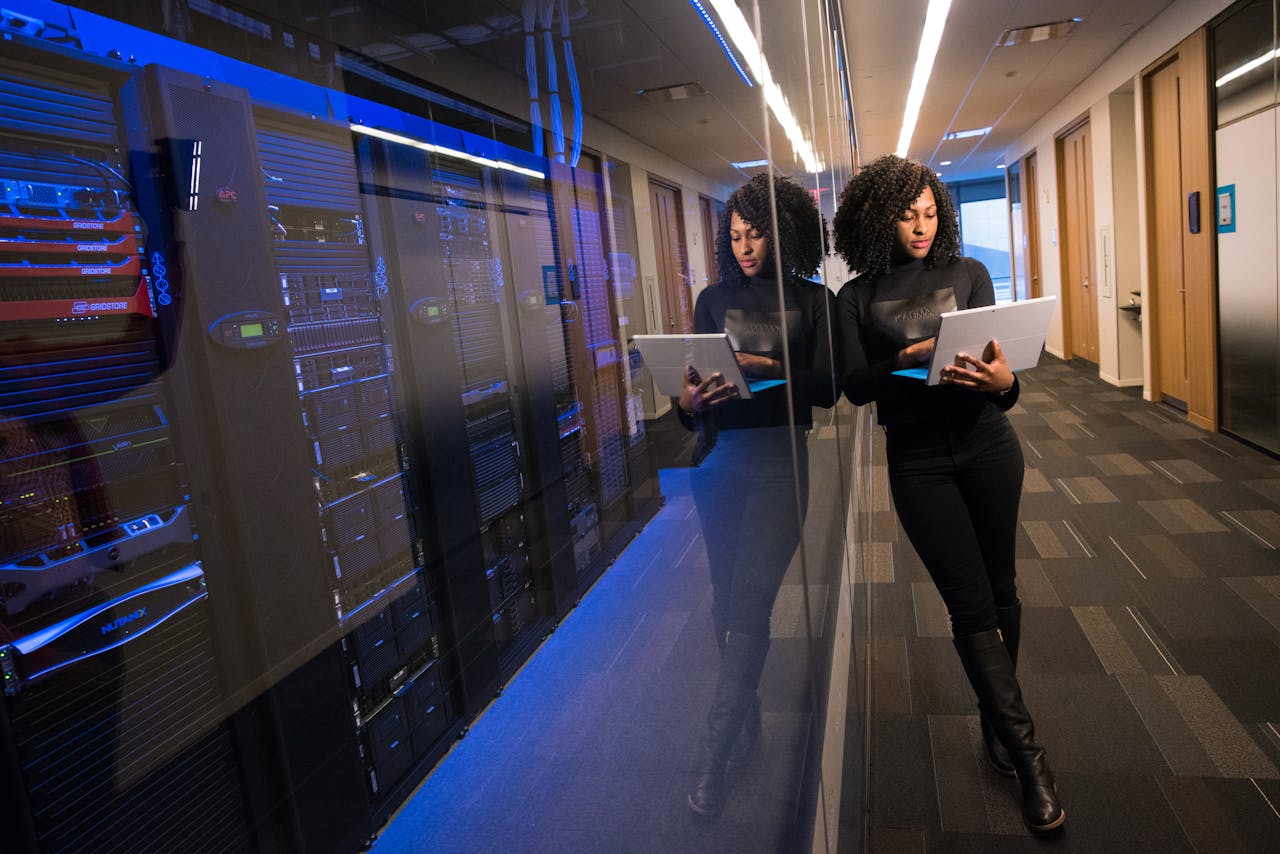 services-06 A woman using a laptop navigating a contemporary data center with mirrored servers.